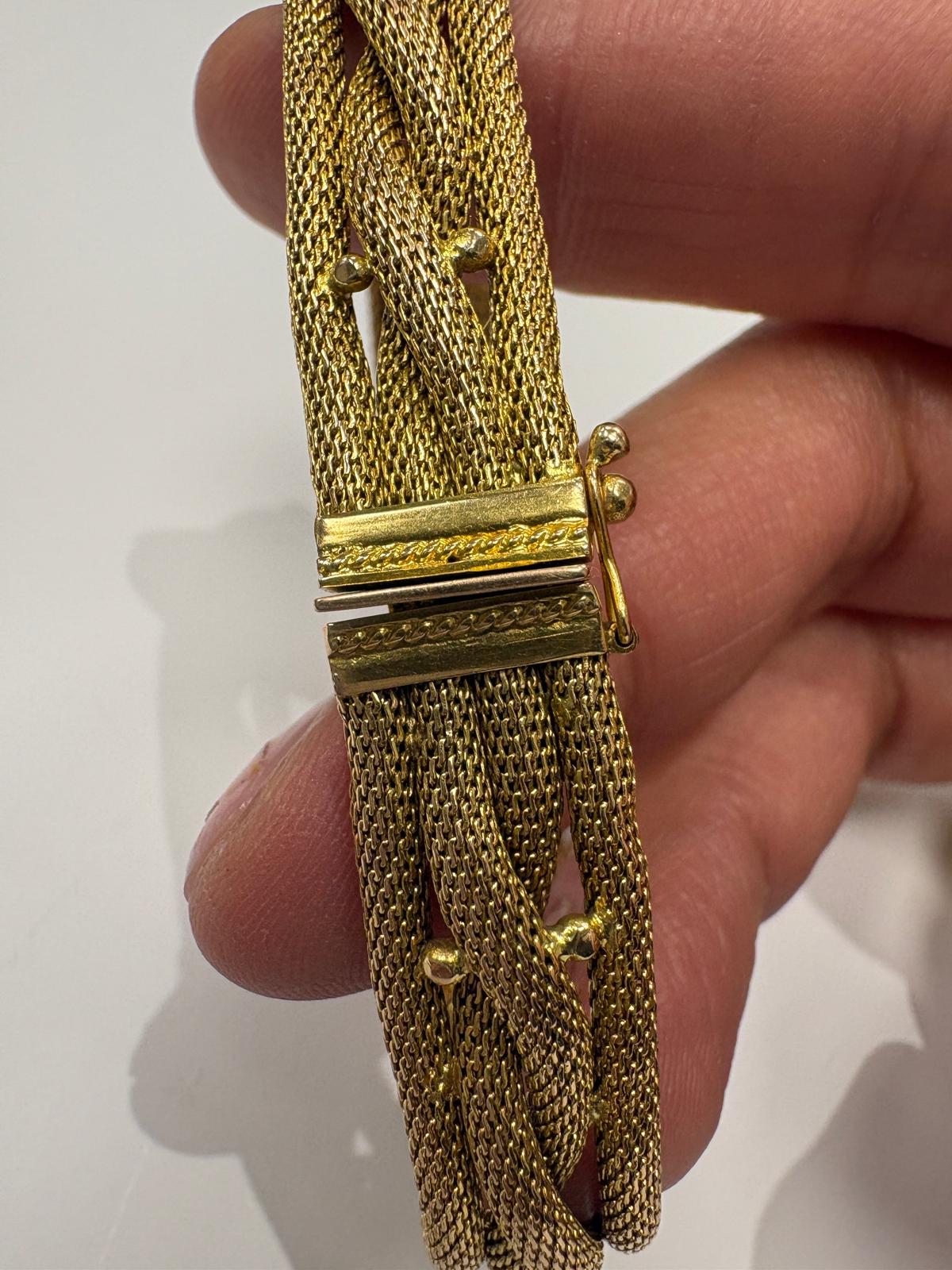 Gold chain bracelet held by a hand on a white background
