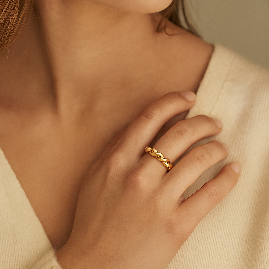 Close-up of a hand wearing a gold ring with a neutral background