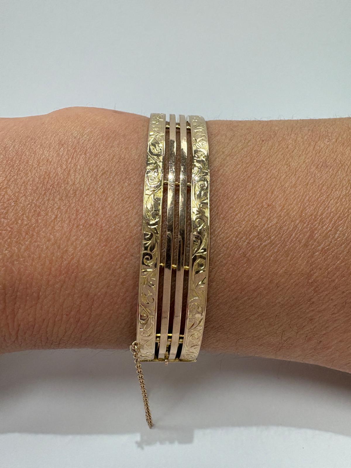 Vintage 9ct gold gate bangle worn on the wrist showing engraved edges