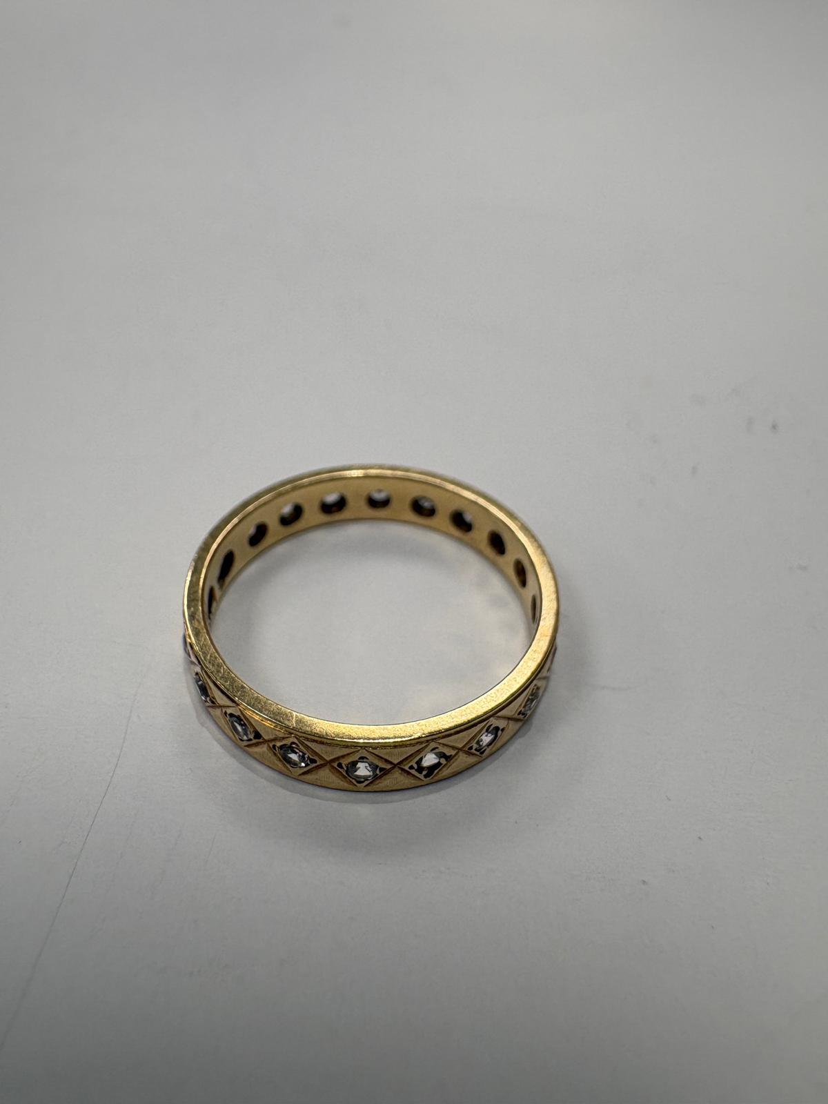 Gold ring with embedded stones on a gray background
