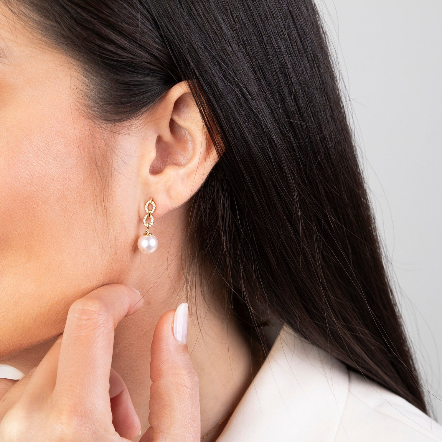 Yellow gold Akoya pearl and diamond double link drop earrings featuring two pavé diamond oval links suspending 8-8.5mm Akoya pearls with butterfly backs, shown on model