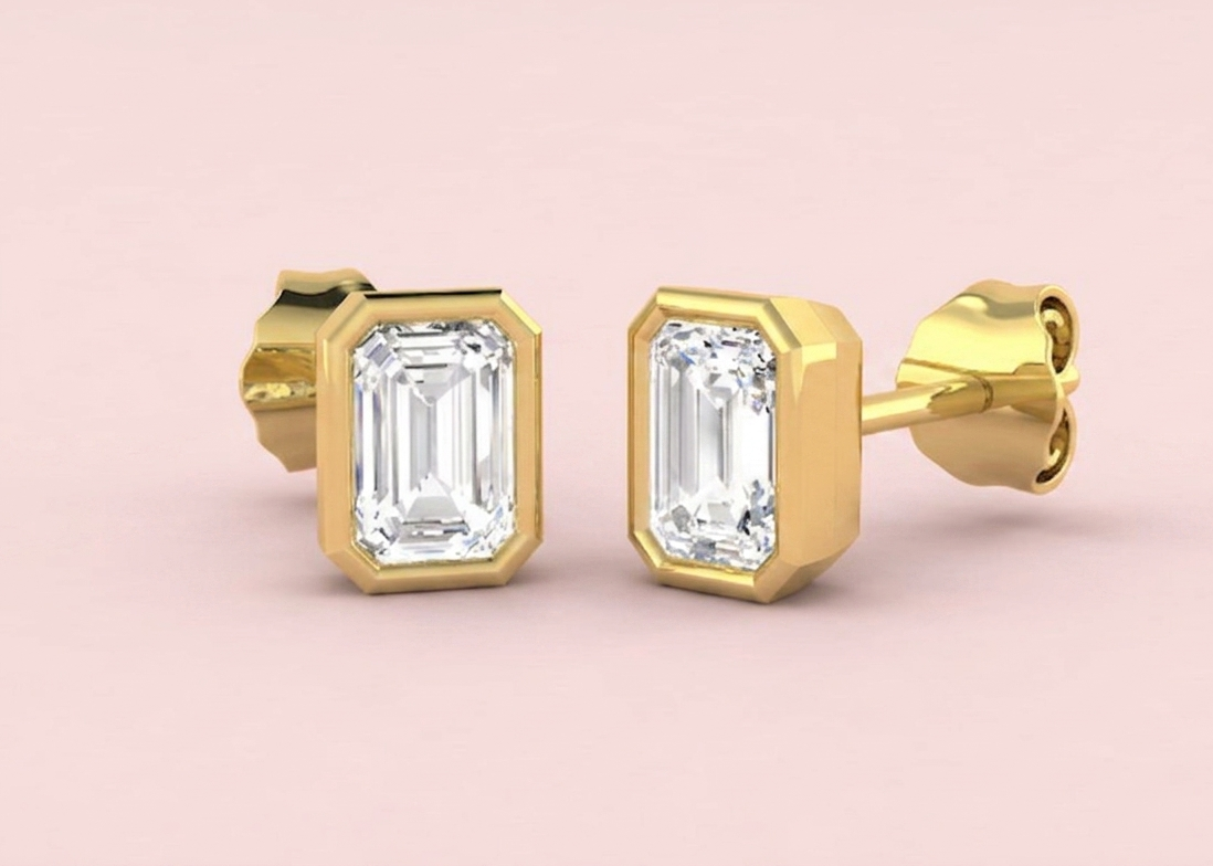 Bezel set lab grown emerald cut diamond stud earrings shown in yellow gold, 1.11ct