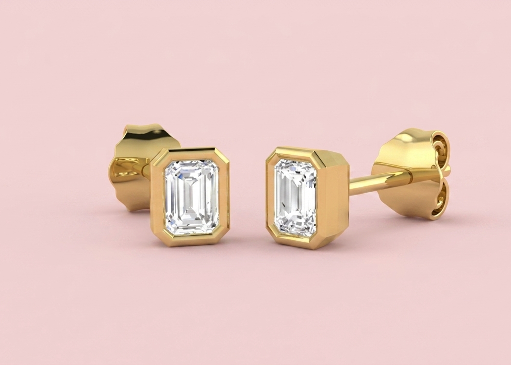 Bezel set lab grown emerald cut diamond stud earrings shown in yellow gold, 0.5ct