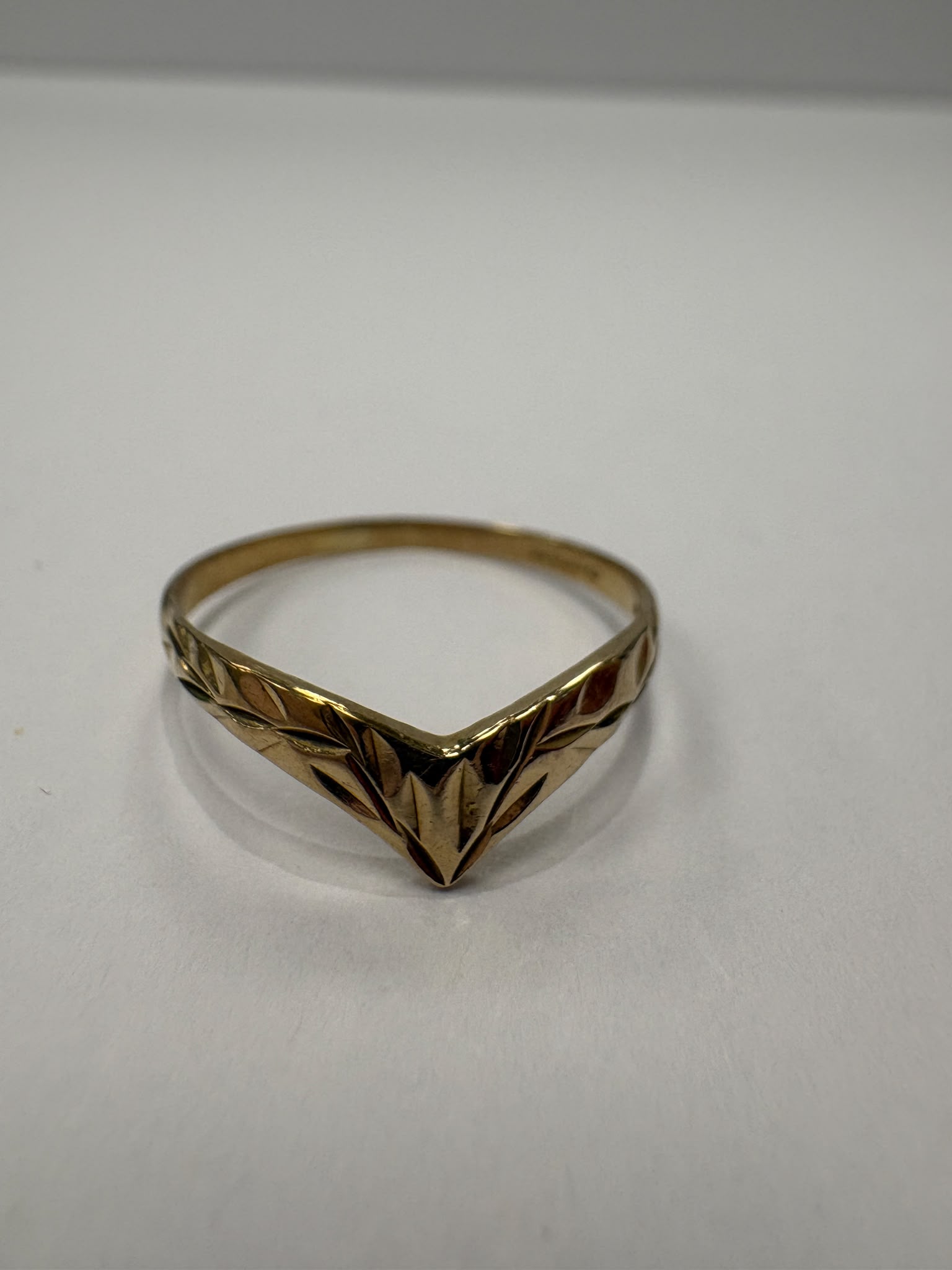 Preloved 9ct yellow gold engraved wishbone ring with half engraved detailing shown on white background and worn on finger, size S, available at Fogal & Barnes Harrogate