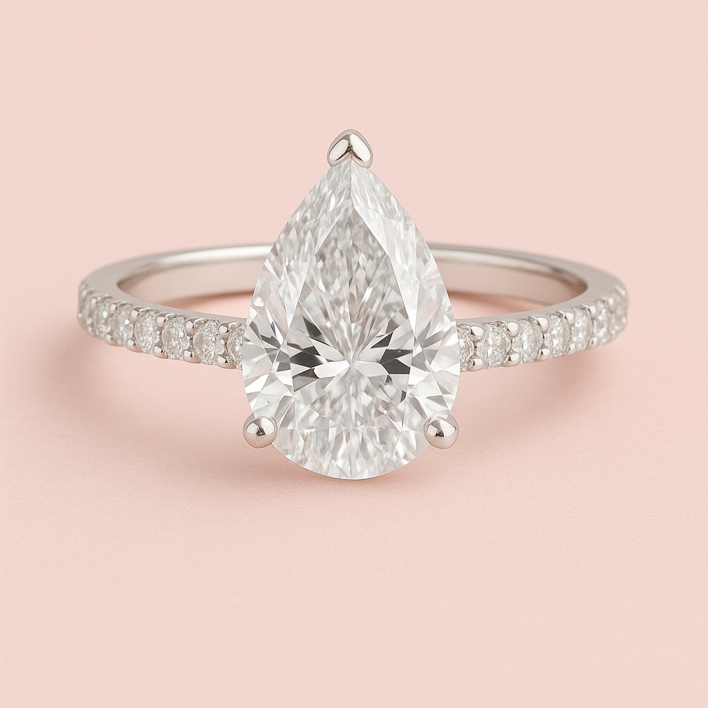Beatrice pear cut lab grown diamond engagement ring with diamond band in white gold on a dusky pink background