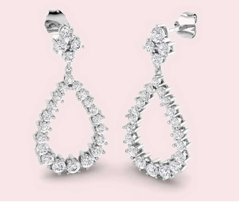 White gold lab-grown diamond pear drop earrings with a cluster top on a pale pink background