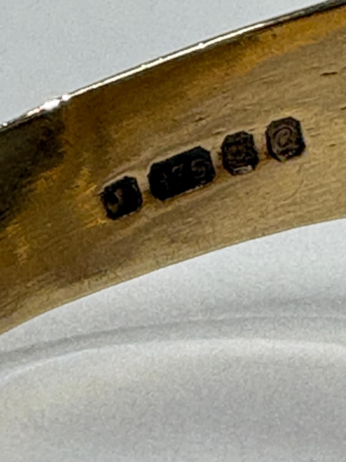 Macro shot of UK hallmark stamps inside 9ct gold signet ring band