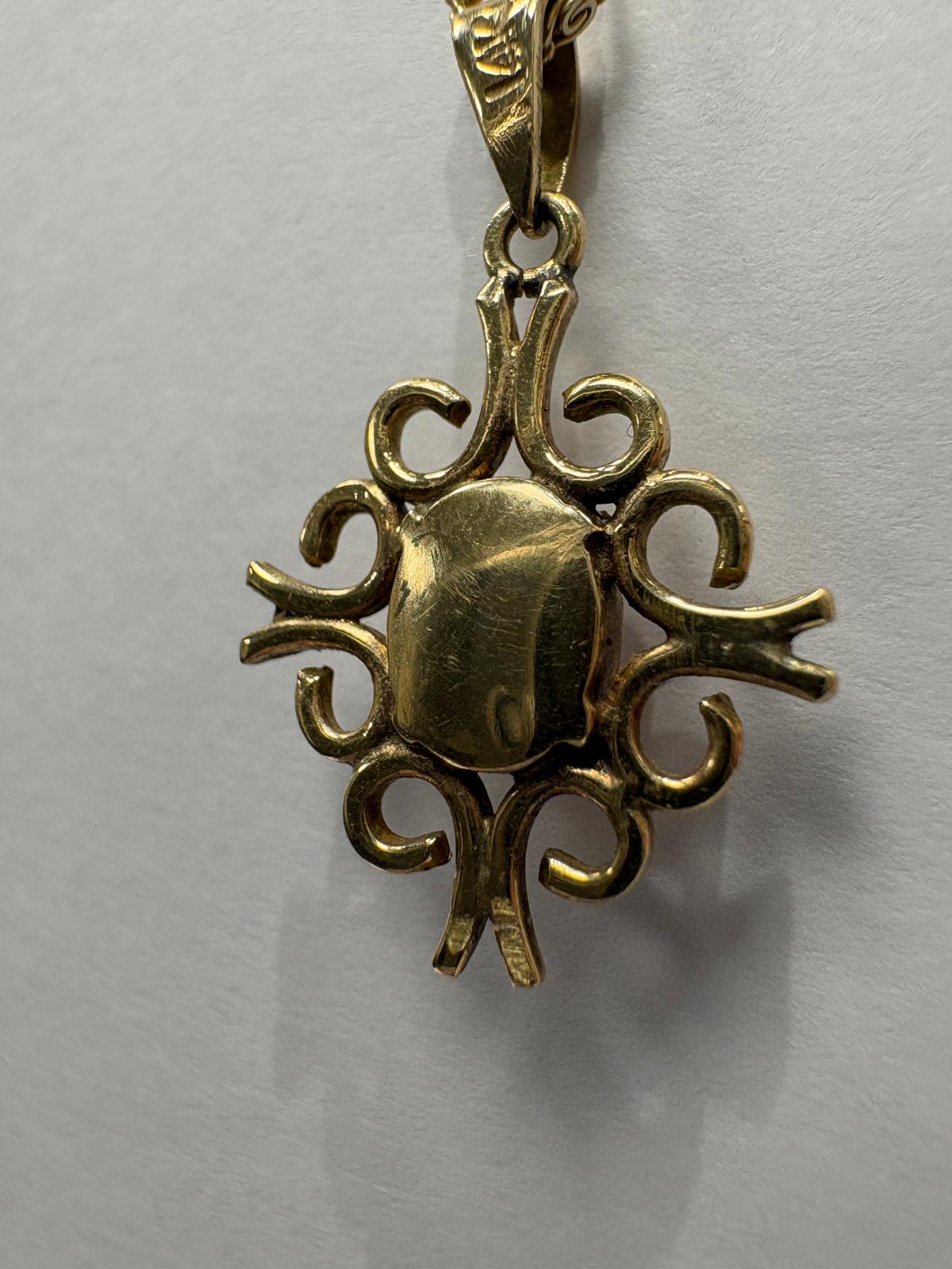 A fine 10k yellow gold fancy link chain suspends a 14ct yellow gold pendant featuring an oval opal cabochon with soft white body colour and pink and blue play-of-colour, held in an ornate open scrollwork setting.