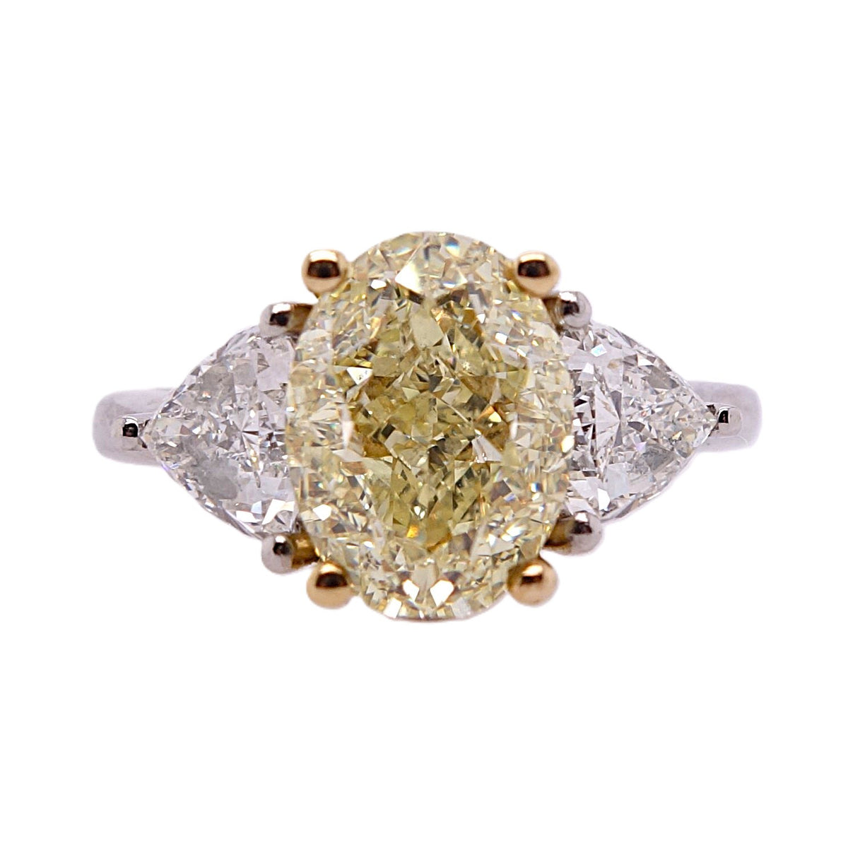 Oval cut natural fancy yellow diamond three stone ring with trillion cut white diamond sides in platinum and yellow gold