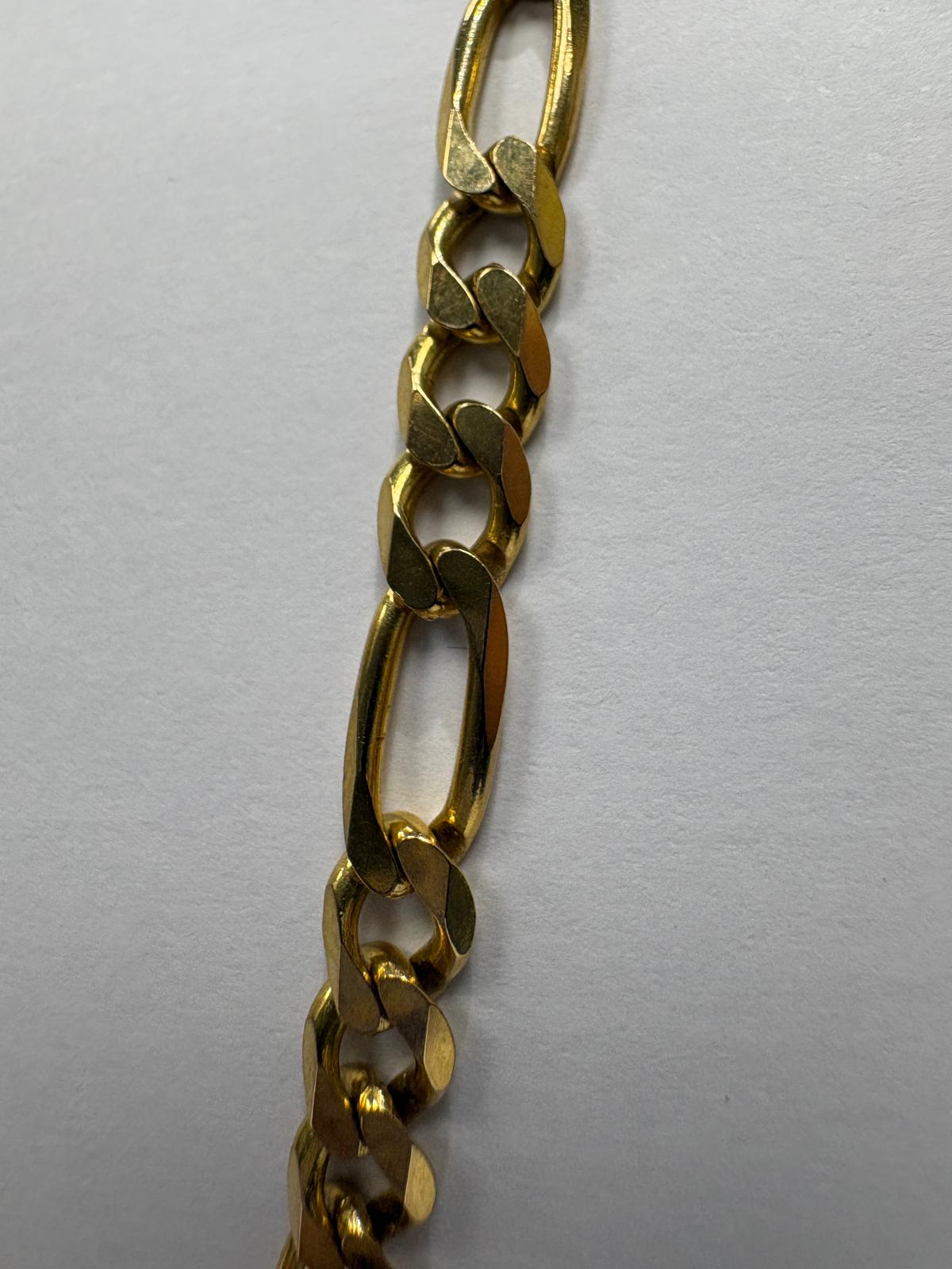 Extreme close-up detail of a pre-loved yellow gold heavy figaro chain showing the individual link construction. The alternating elongated oval links and small round curb links are shown with their polished bevelled surfaces catching the light.