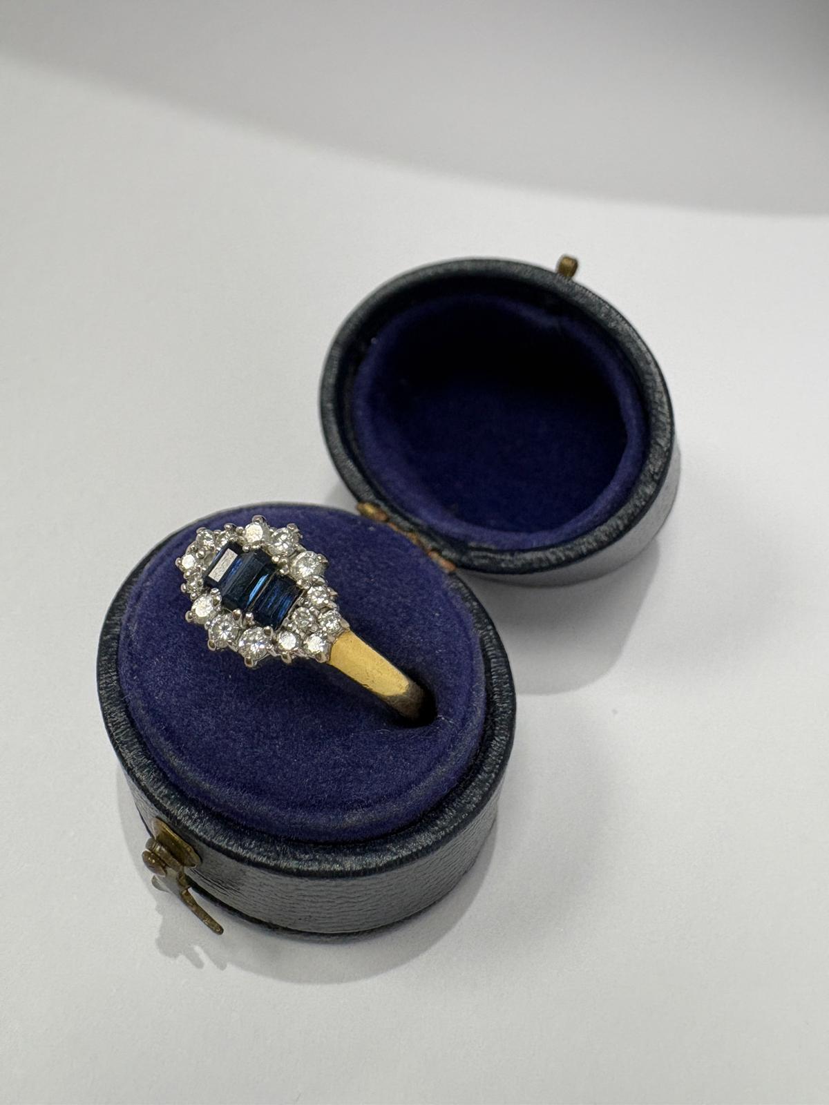 Side profile view of a pre-loved yellow gold natural sapphire and diamond marquise cluster ring worn on a finger. The substantial yellow gold shank and the elevated white gold open-back cluster setting are clearly visible, showing the depth and architectural construction of the ring head.