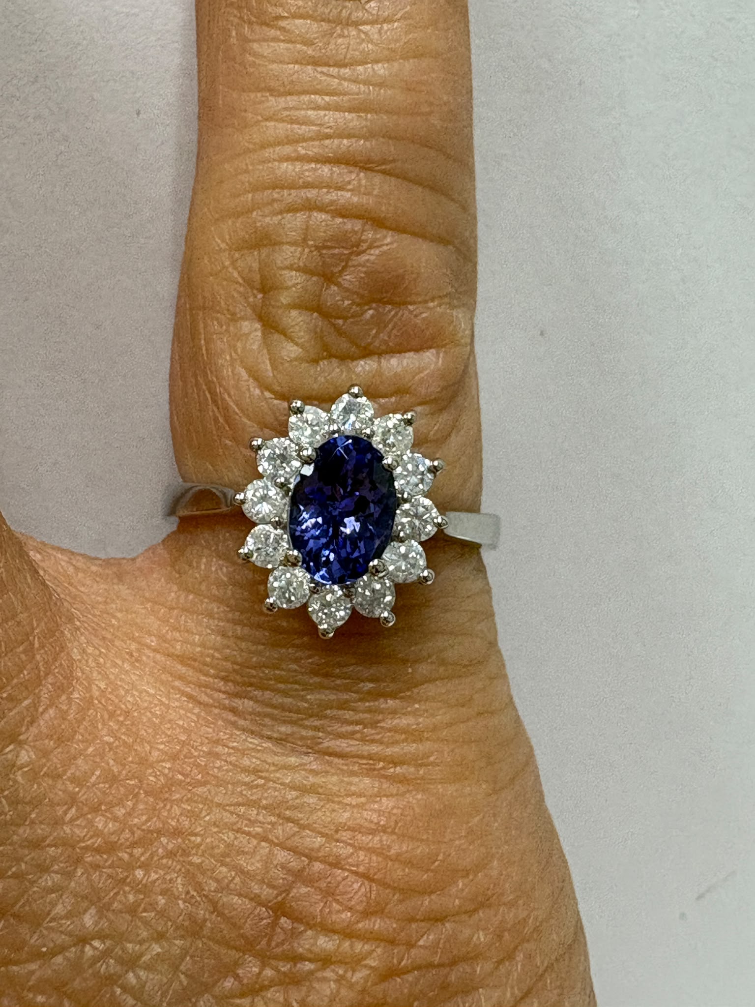 Pre-loved tanzanite diamond cluster ring, side angle on hand