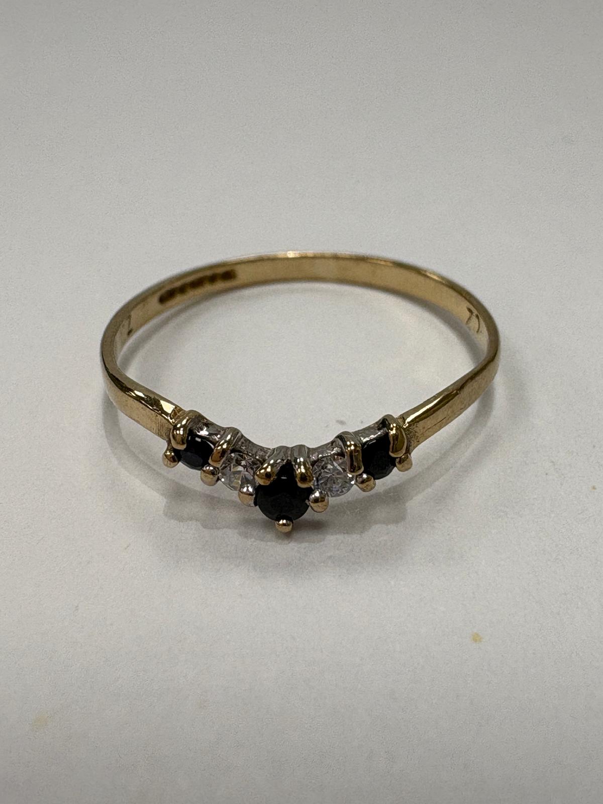 Vintage 9ct yellow gold sapphire and cubic zirconia wishbone ring size K½ with alternating blue sapphire and white CZ stones in V shape setting, shown on ring cone and close up on white background, available at Fogal & Barnes Harrogate