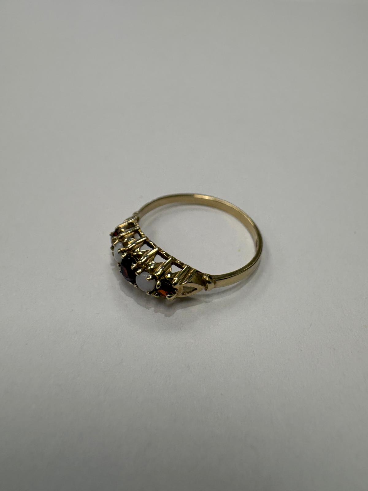 Side view of 9ct gold garnet and opal five stone ring showing carved scroll gallery