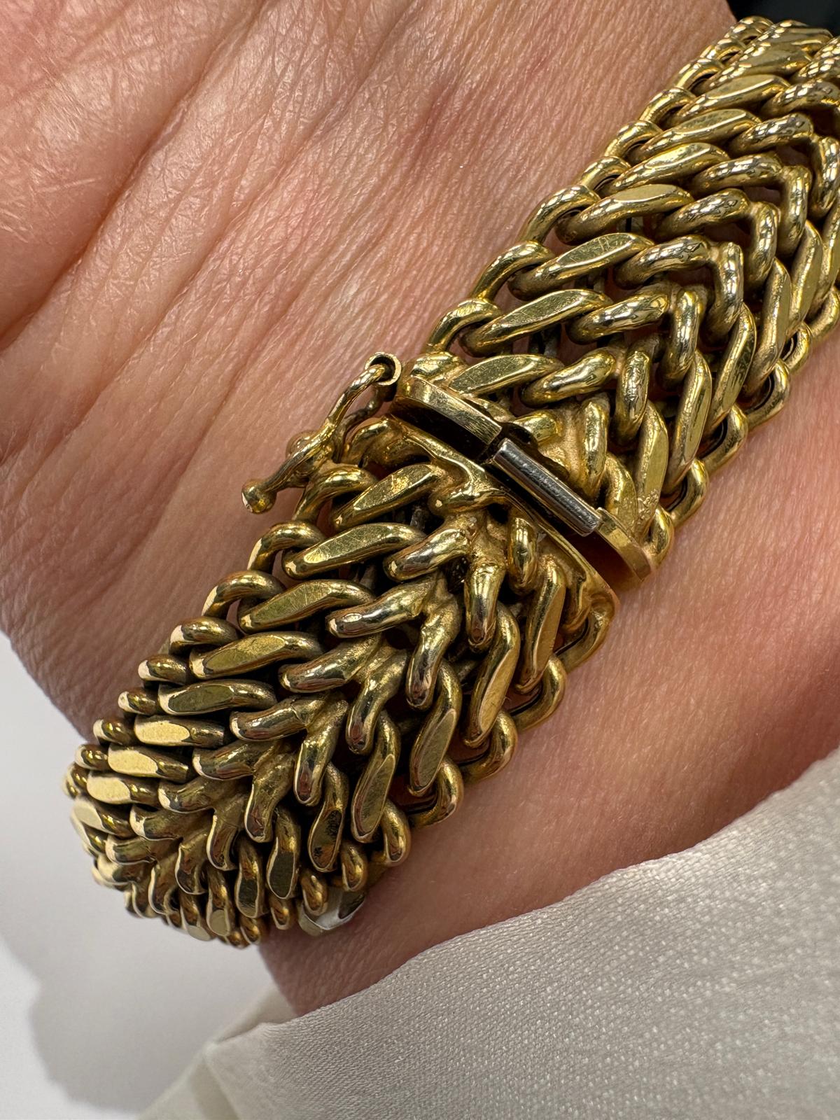 Gold chain bracelet on a person's wrist with a neutral background
