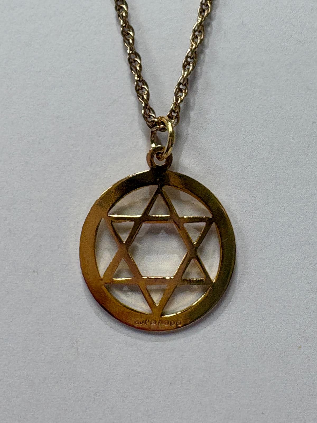 Close-up of gold Star of David pendant showing hallmark and chain link