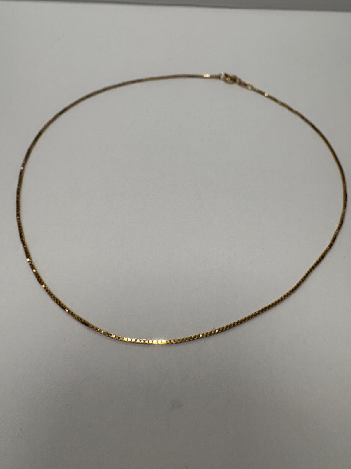 9ct gold Balestra box chain laid in a circle on white background