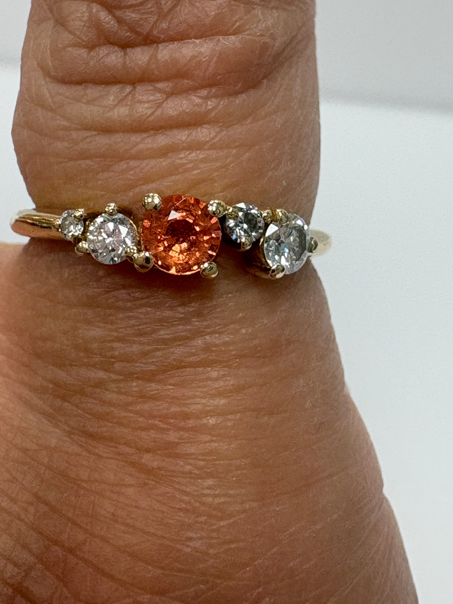 Close-up of orange sapphire centre stone with moissanite accents