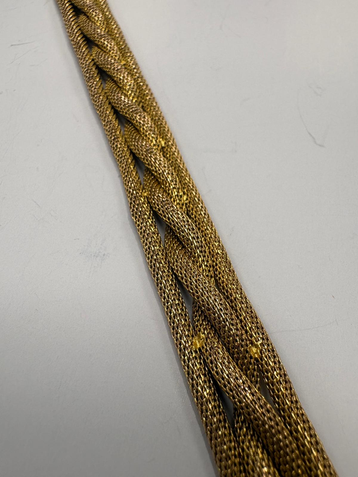Close-up of braided gold bracelet on a light gray background harrogate jewellers