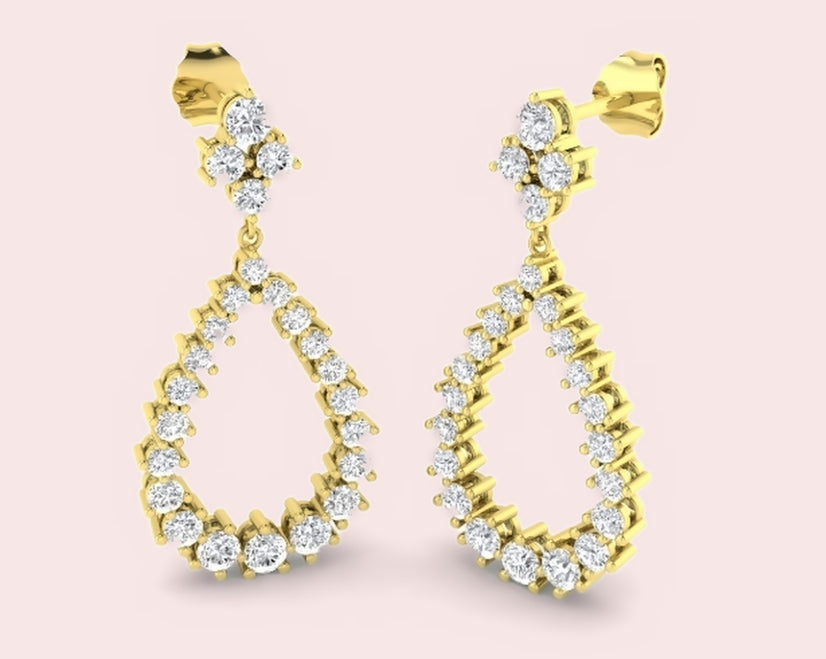 Yellow gold lab-grown diamond pear drop earrings with a cluster top on a pale pink background