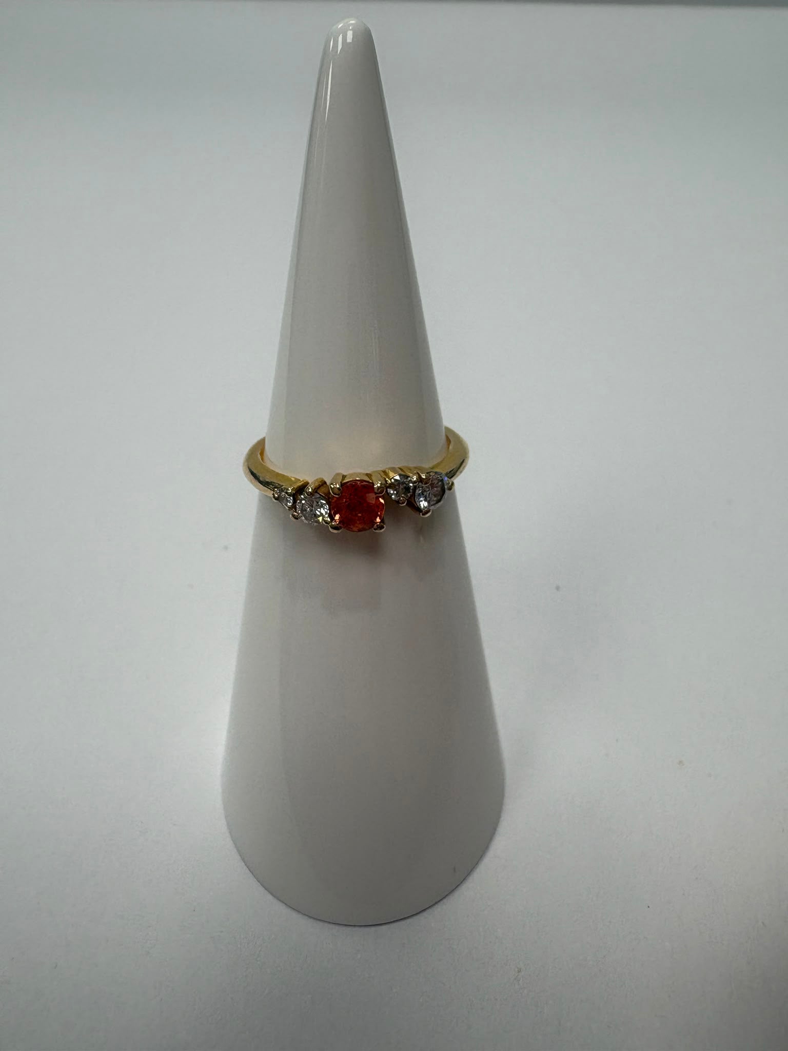 Orange sapphire and moissanite five-stone ring on hand