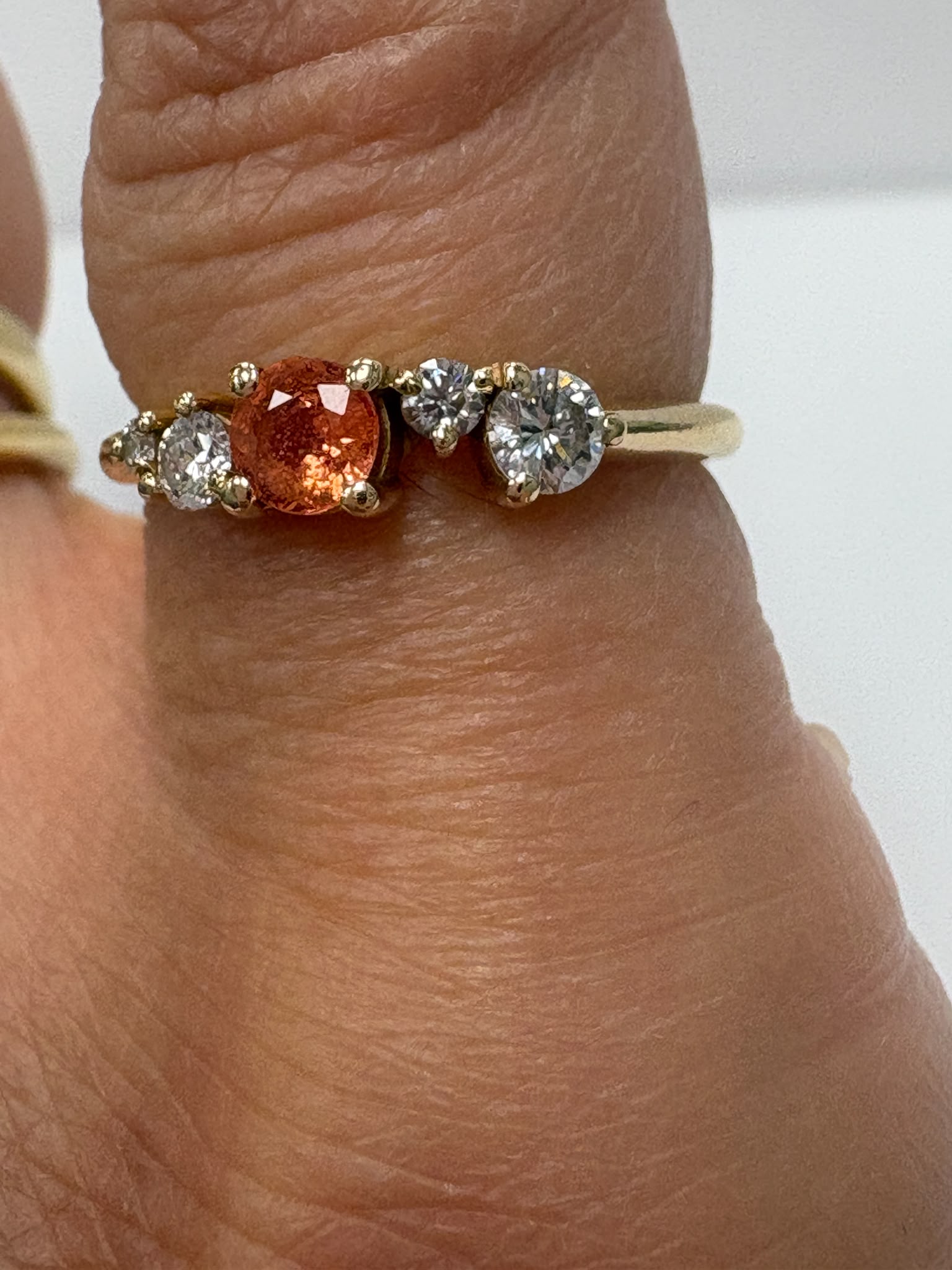 Orange sapphire and moissanite ring shown on ring stand