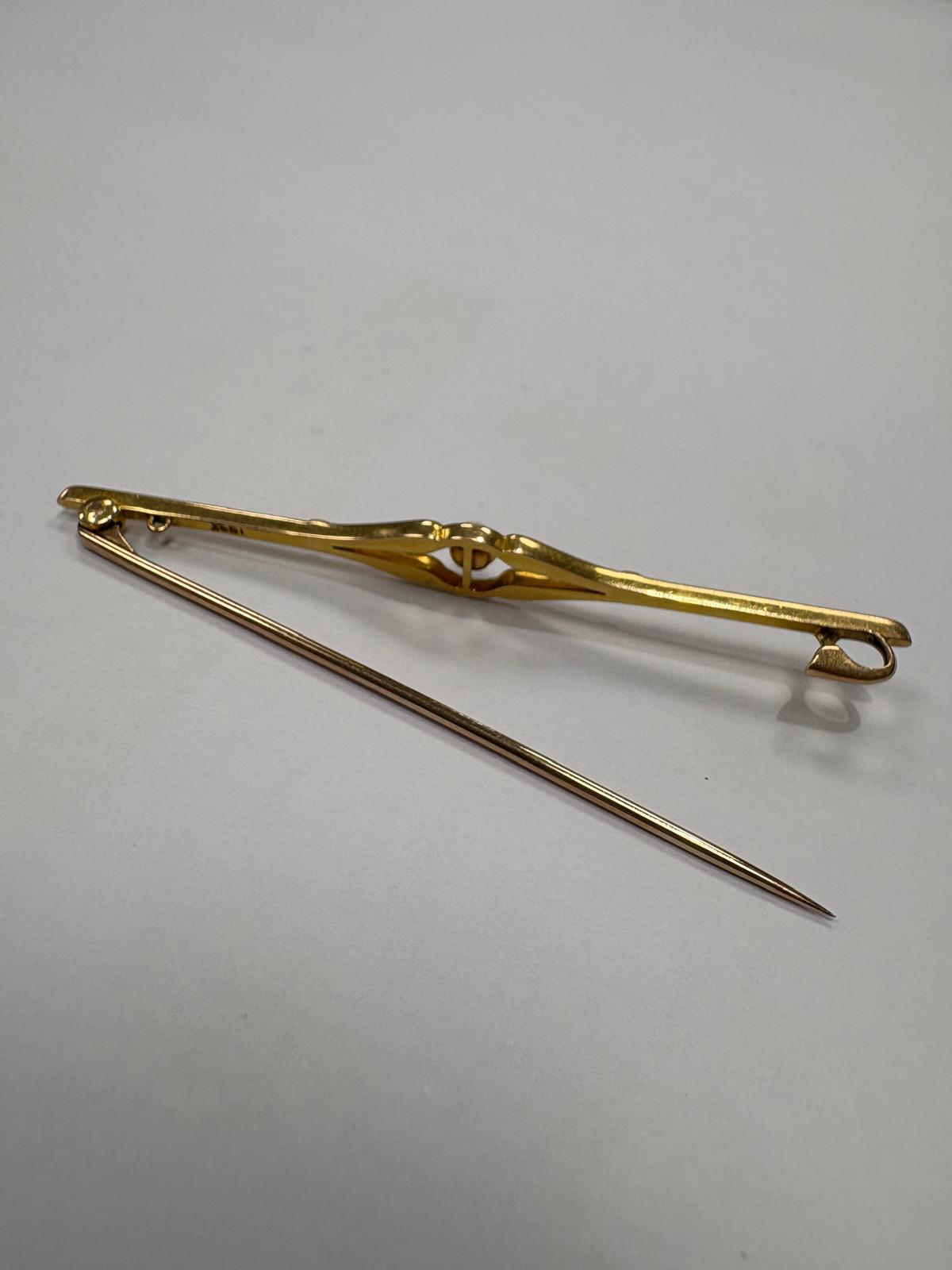 Reverse view of a pre-loved Edwardian 18ct yellow gold natural pearl bar brooch with the pin fully extended. The plain polished gold back of the brooch is shown with the pin hinge mechanism, catch and loop clasp clearly visible. Hallmark stamp visible on the bar.