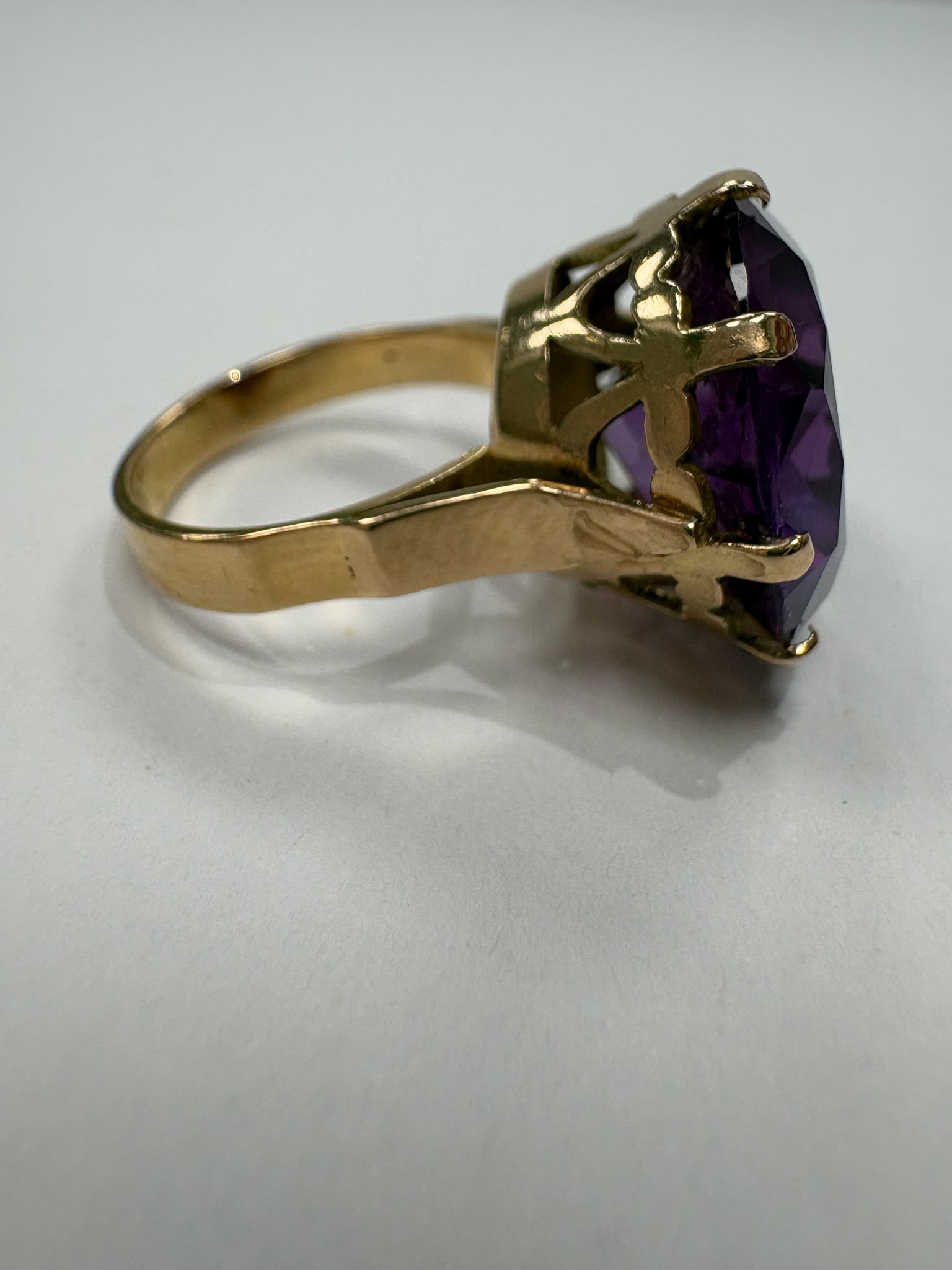 Studio photo of large round-cut purple CZ in gold claw setting