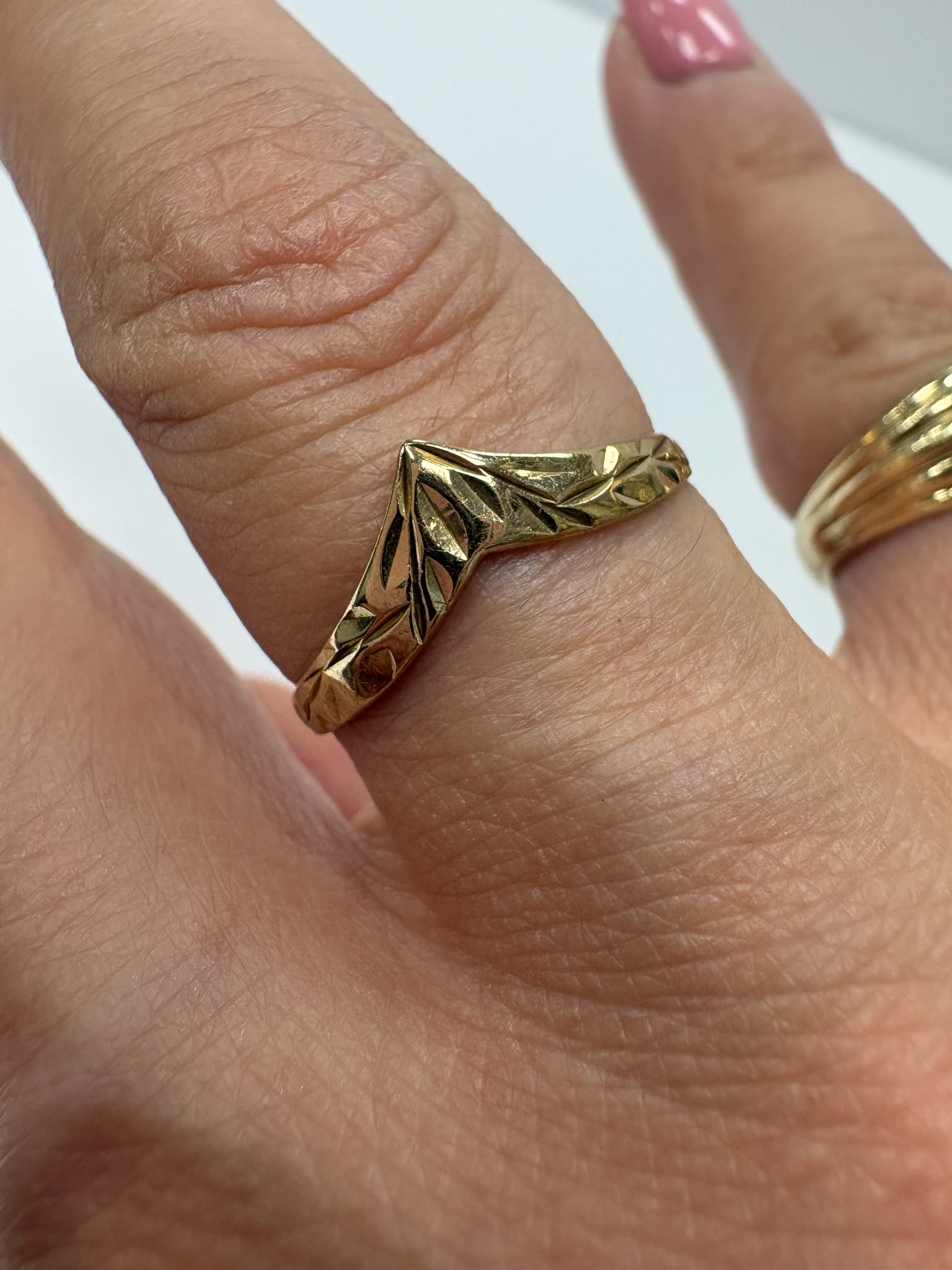 Preloved 9ct yellow gold engraved wishbone ring with half engraved detailing shown on white background and worn on finger, size S, available at Fogal & Barnes Harrogate