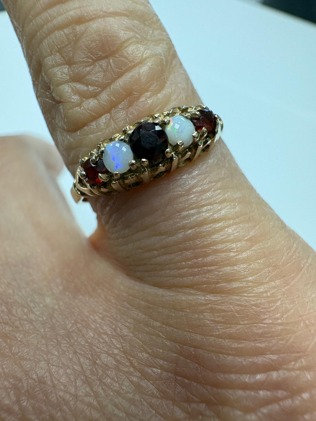 Gold ring with gemstones on a finger against a white background