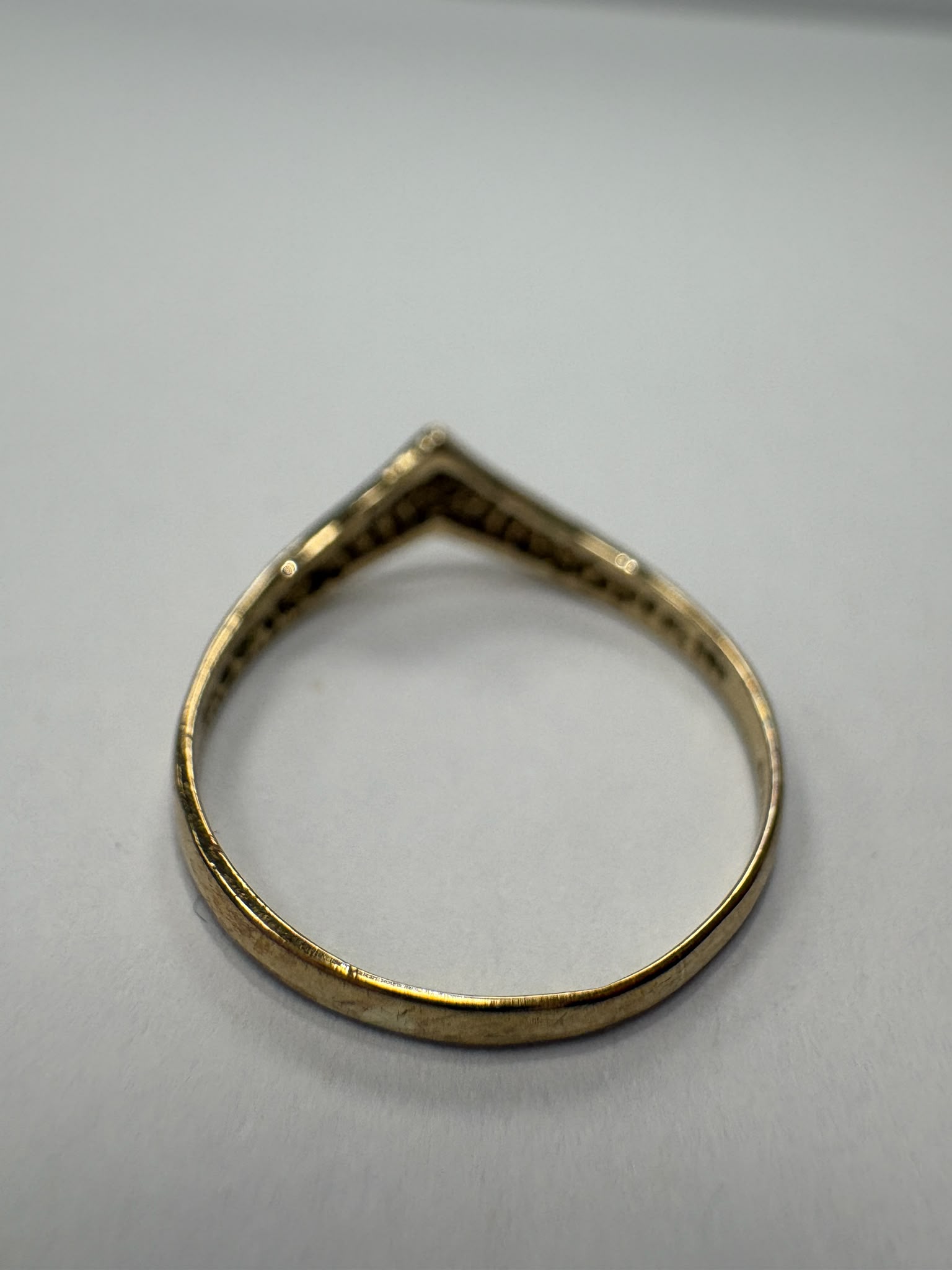 Preloved 9ct yellow gold engraved wishbone ring with half engraved detailing shown on white background and worn on finger, size S, available at Fogal & Barnes Harrogate