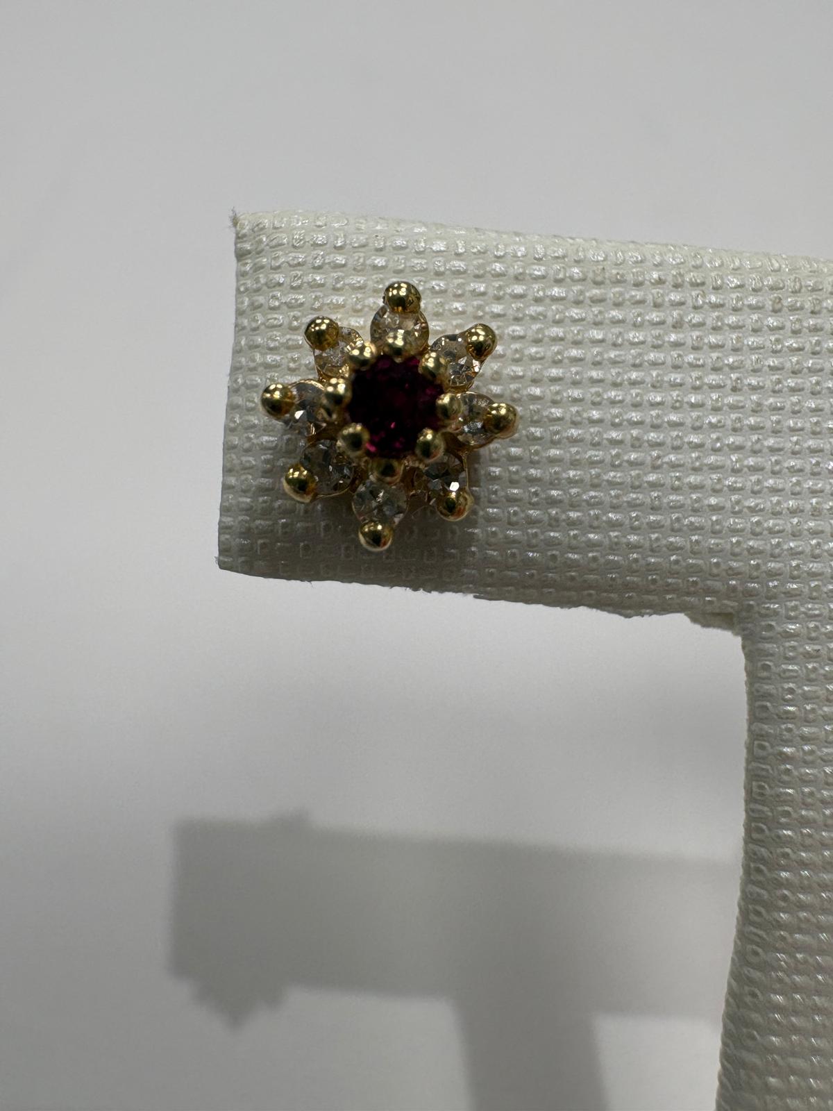 Gold earring on a white display stand with a plain background
