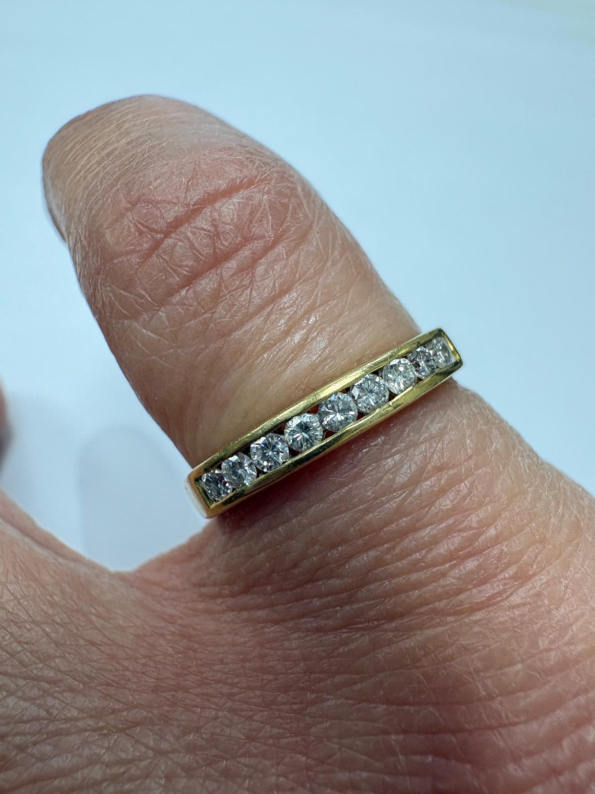 Pre-loved 18ct yellow gold channel-set diamond half eternity ring shown on hand, size M
