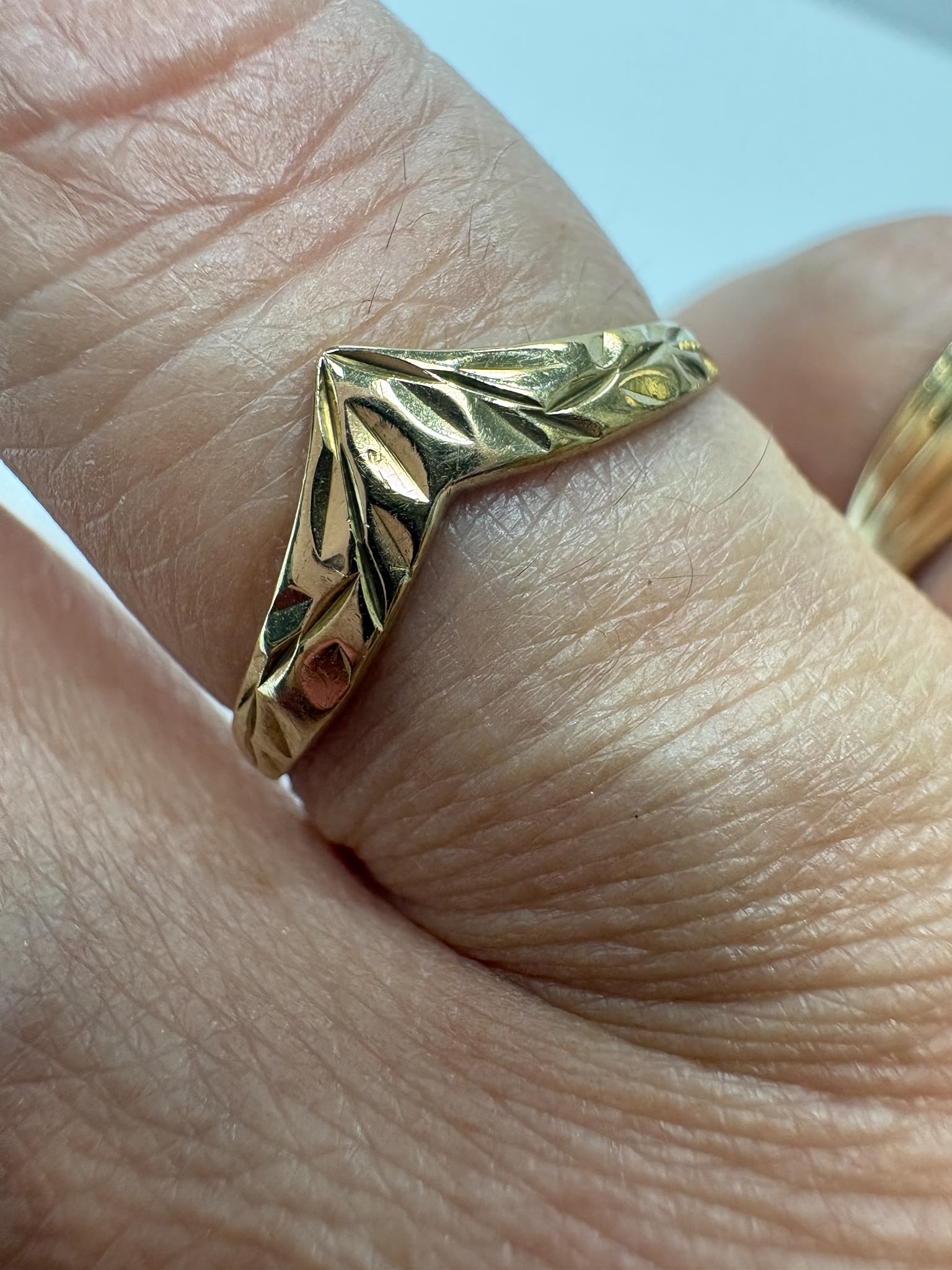 Preloved 9ct yellow gold engraved wishbone ring with half engraved detailing shown on white background and worn on finger, size S, available at Fogal & Barnes Harrogate