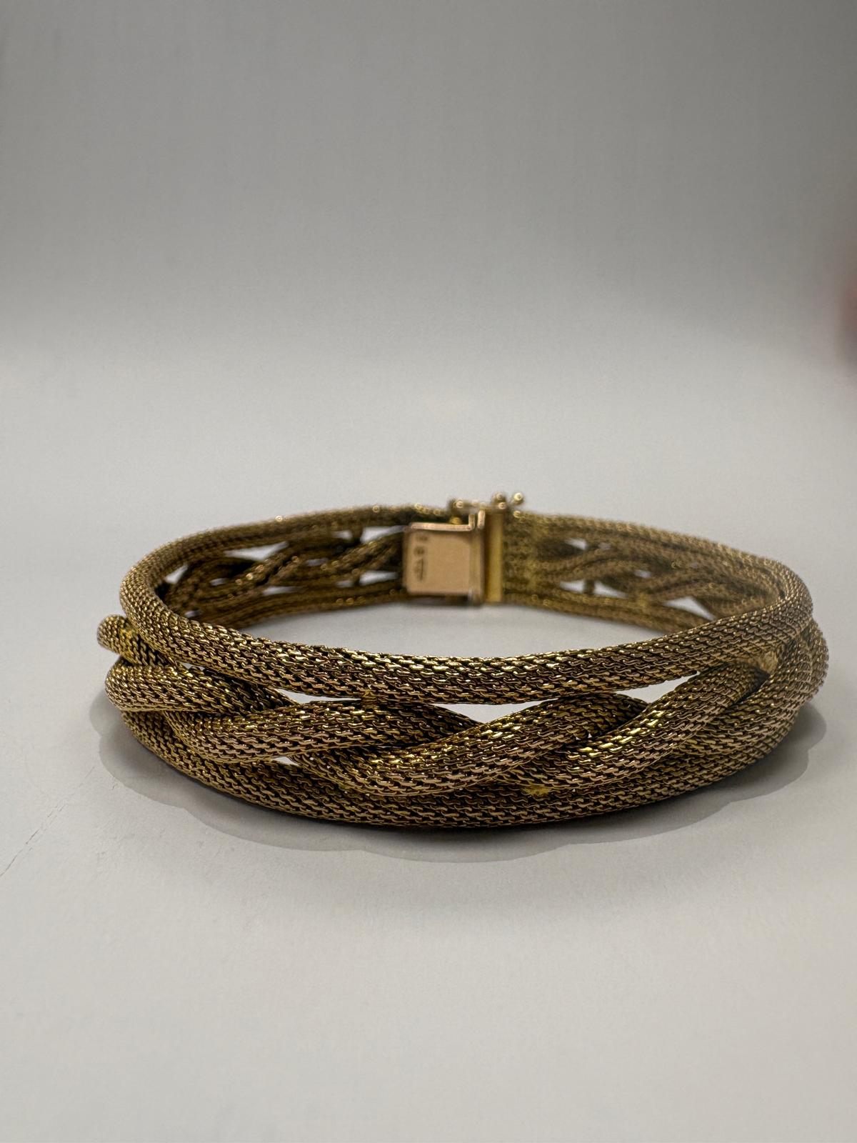 Gold braided bracelet on a light gray background