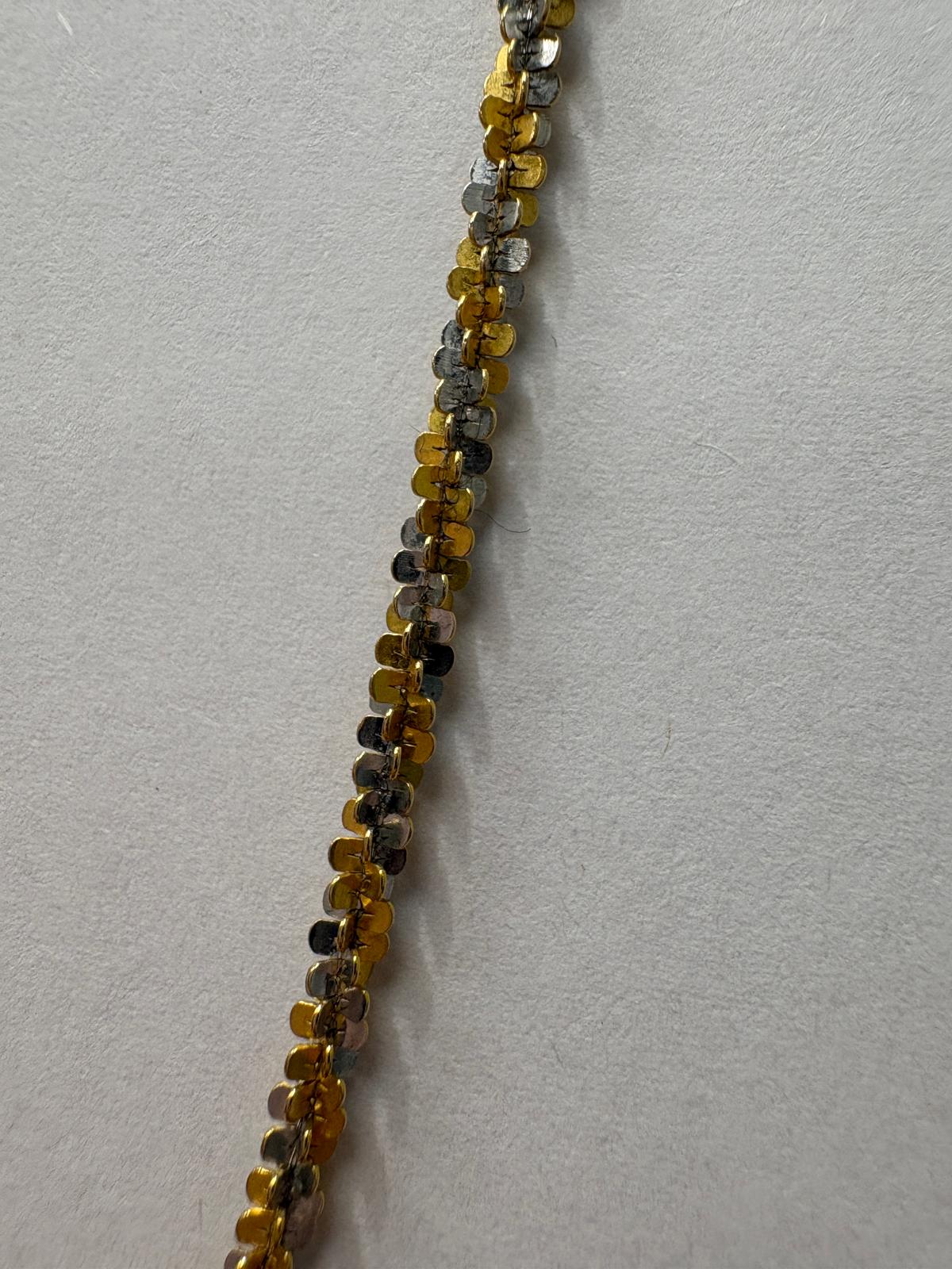 Close-up of two-tone gold linkwork on textured sparkle chain